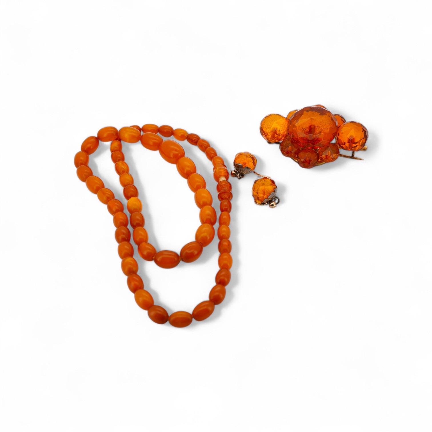 A single strand graduated oval amber bead necklace, 40cm, gross weight 9 grams, together with an amber cluster set brooch and pair of earrings.